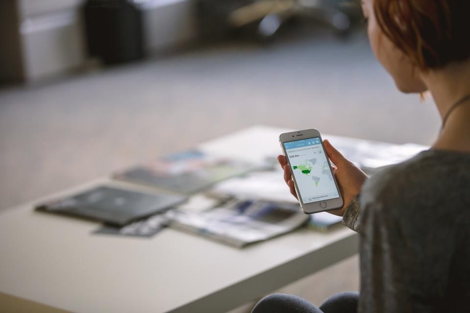 A woman holds a phone showing a map app.